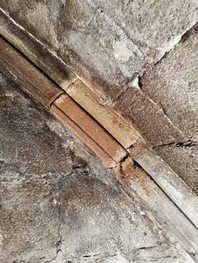 Detall de grapa metàl·lica oxidada entre carreus abans de la intervenció
