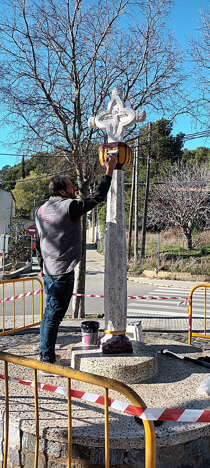 Restaurador treballant a la creu de terme danyada per l’acte vandàlic