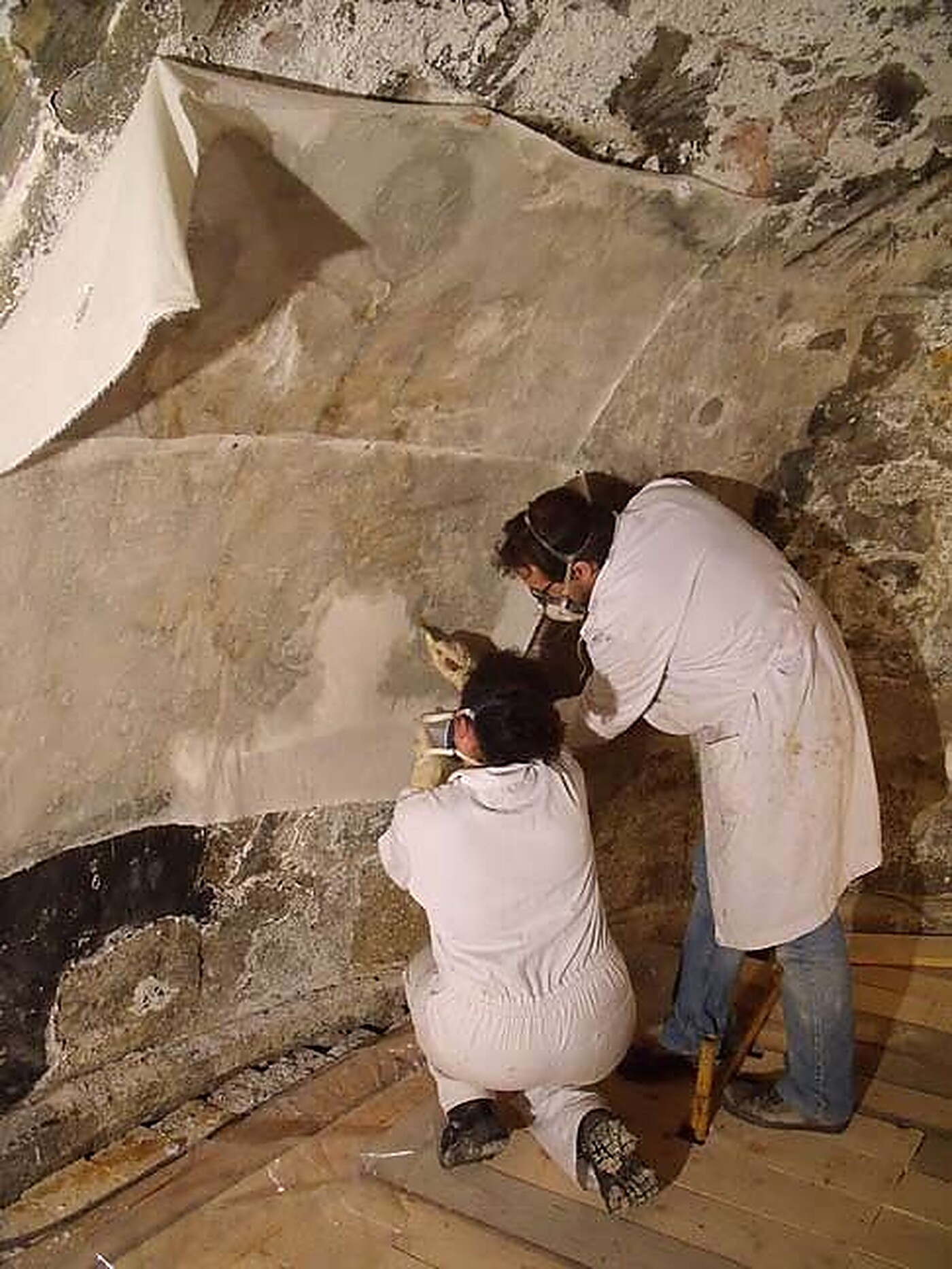 Procés: dos restauradors engassant la pintura mural