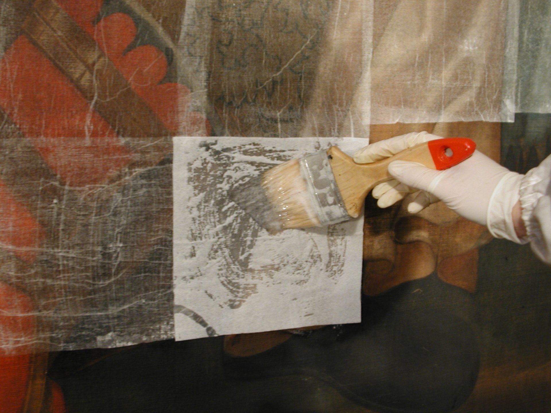 Detall de la fixació de la pintura amb apòsits de paper japonès